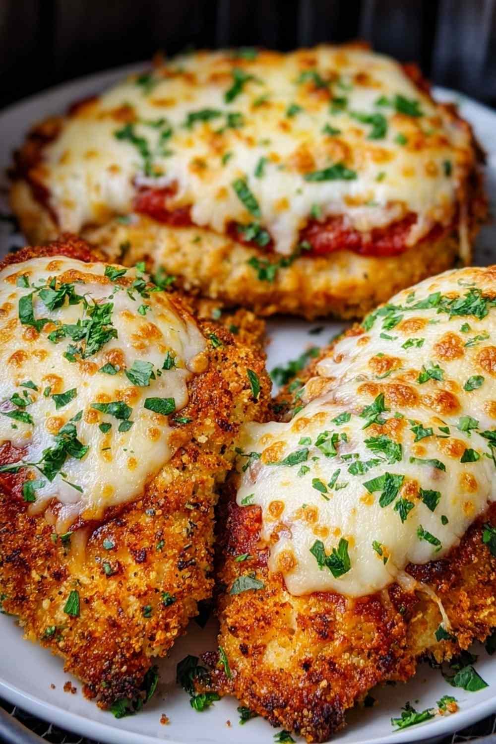 Air fryer chicken parmesan on white plate with melted mozzarella cheese and marinara sauce