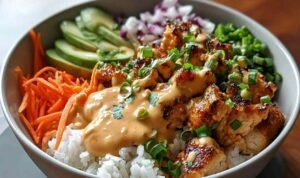 Bang Bang Chicken Bowl with tender chicken, colorful vegetables, and creamy spicy sauce over rice in a white bowl