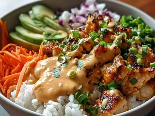 Bang Bang Chicken Bowl with tender chicken, colorful vegetables, and creamy spicy sauce over rice in a white bowl