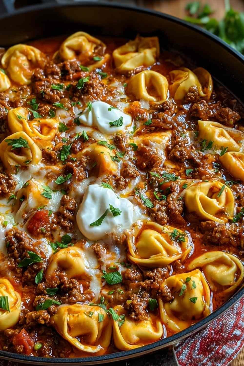 Cheesy beef enchiladas tortellini with melted cheddar cheese in baking dish