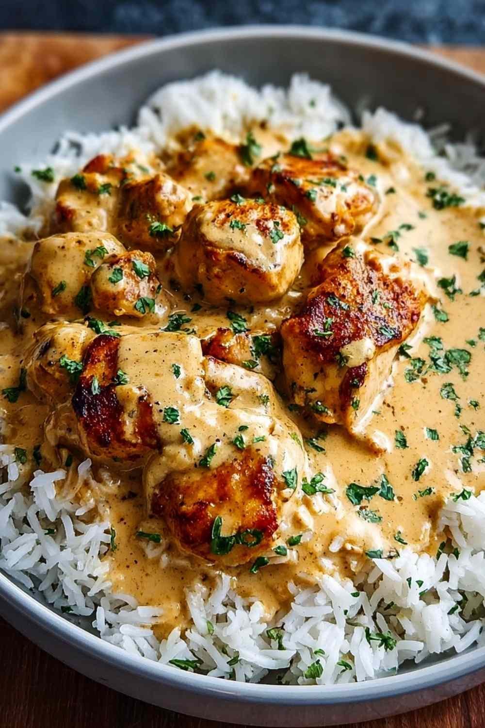 Creamy smothered chicken and rice served on white plate with parsley garnish and parmesan cheese