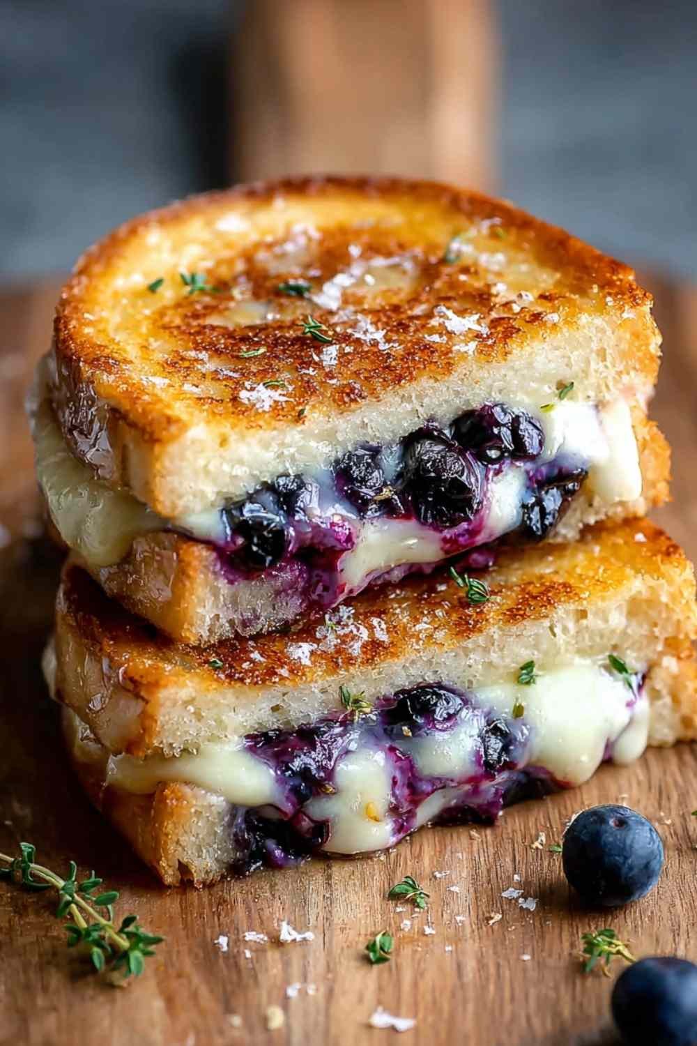 Crispy blueberry grilled cheese sandwich cut in half showing melted white cheddar and mozzarella with blueberry jam