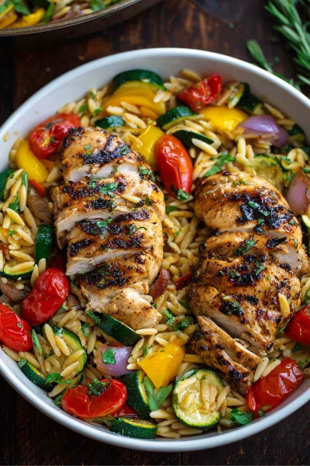 Easy balsamic chicken veggie orzo in large skillet with sliced chicken, colorful vegetables, and herbs