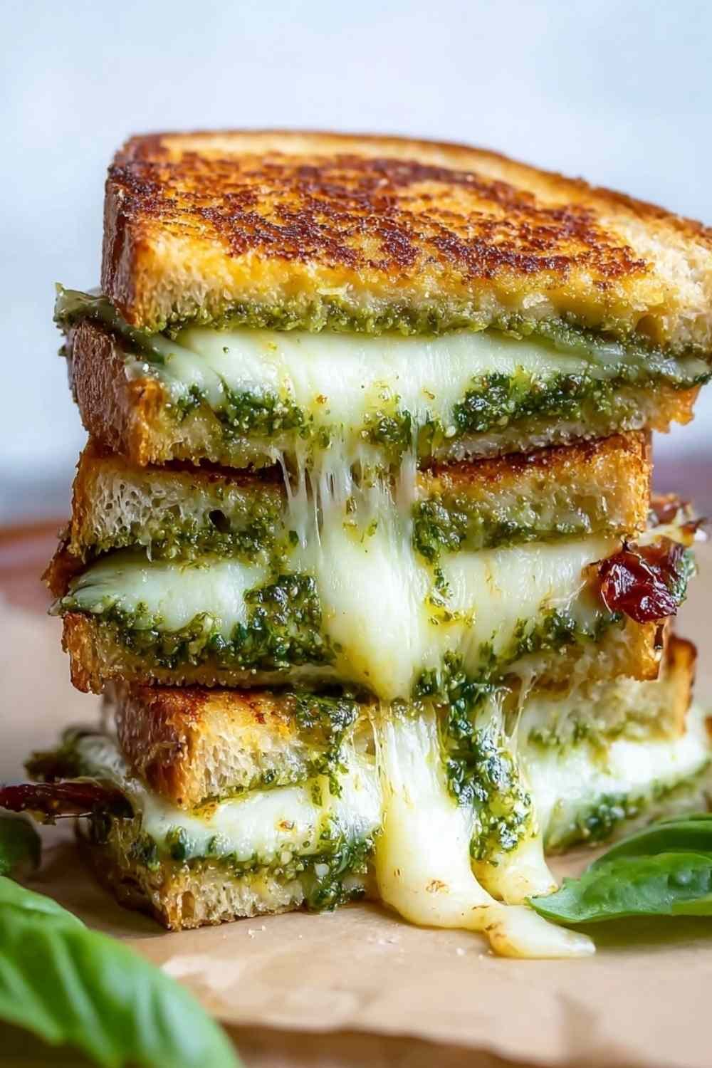 Sourdough pesto grilled cheese cut in half showing melted mozzarella cheese and pesto filling