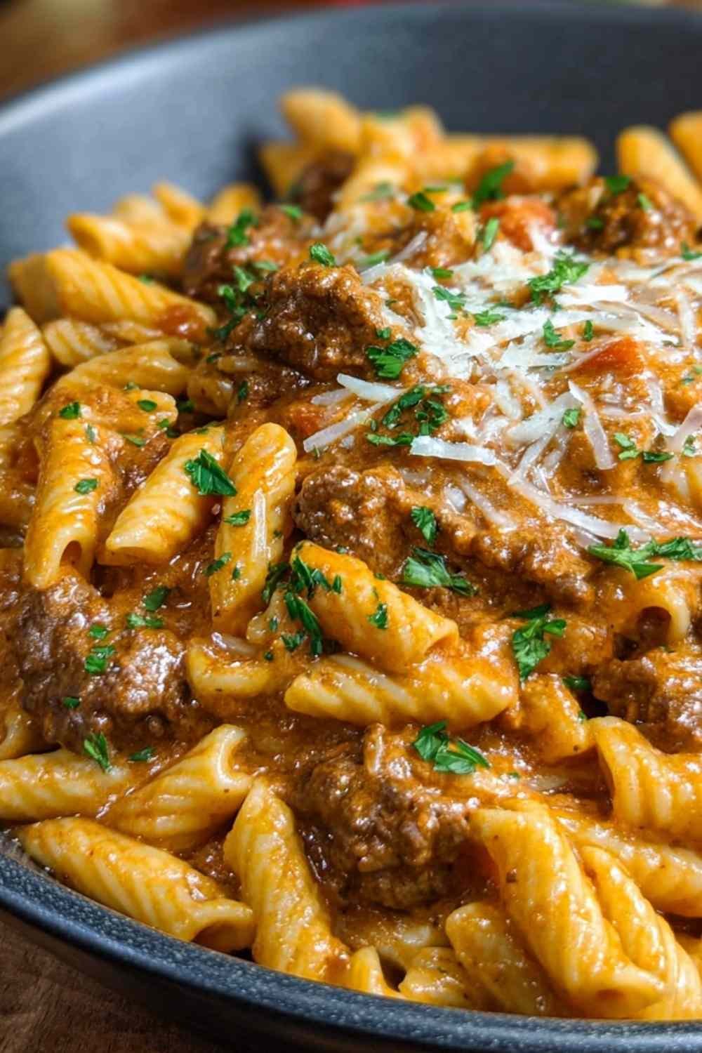 High protein creamy beef pasta in large skillet with fresh basil garnish
