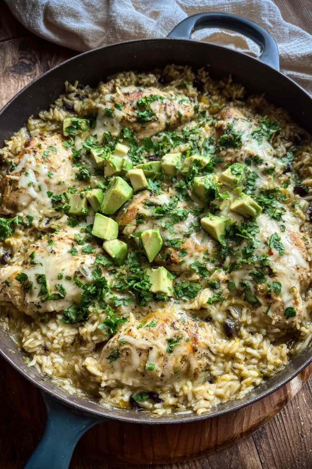 Salsa Verde Chicken Rice Skillet topped with melted cheese, cilantro, and avocado in large skillet