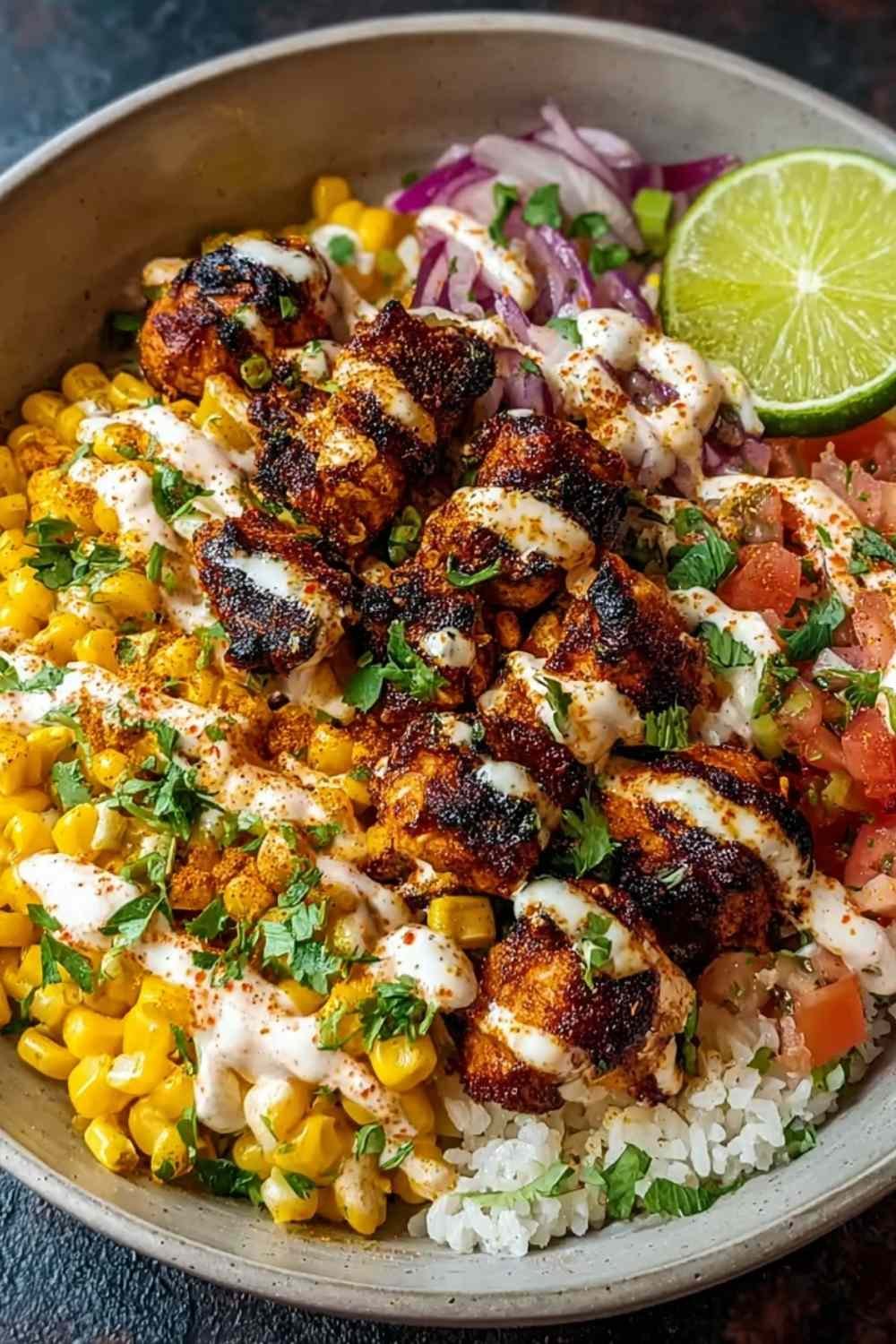 Street corn chicken bowl with sliced chicken, creamy charred corn mixture, rice, cotija cheese, and cilantro in white bowl