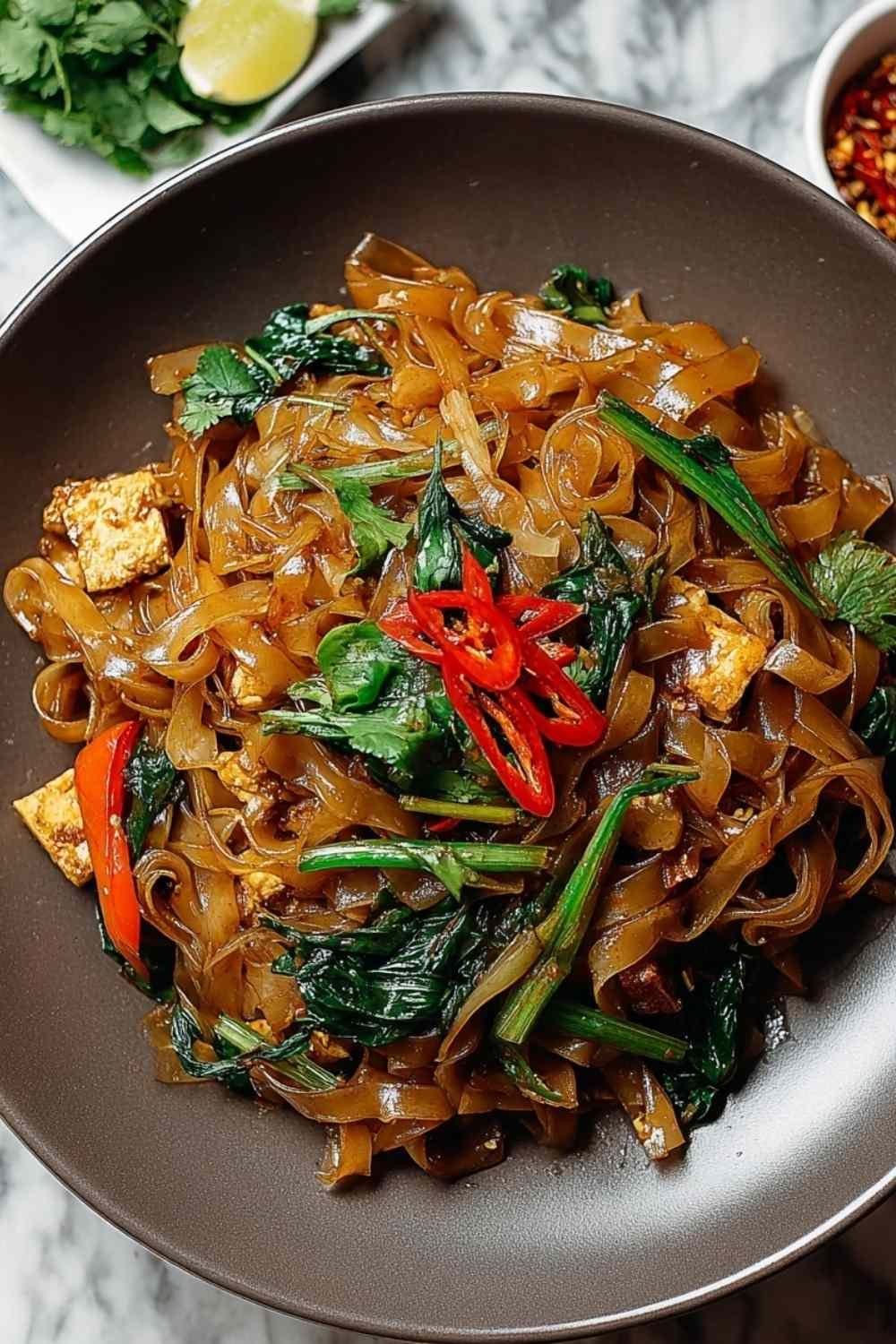 Thai Drunken Noodles with vegetables and chicken being tossed in wok ready to serve