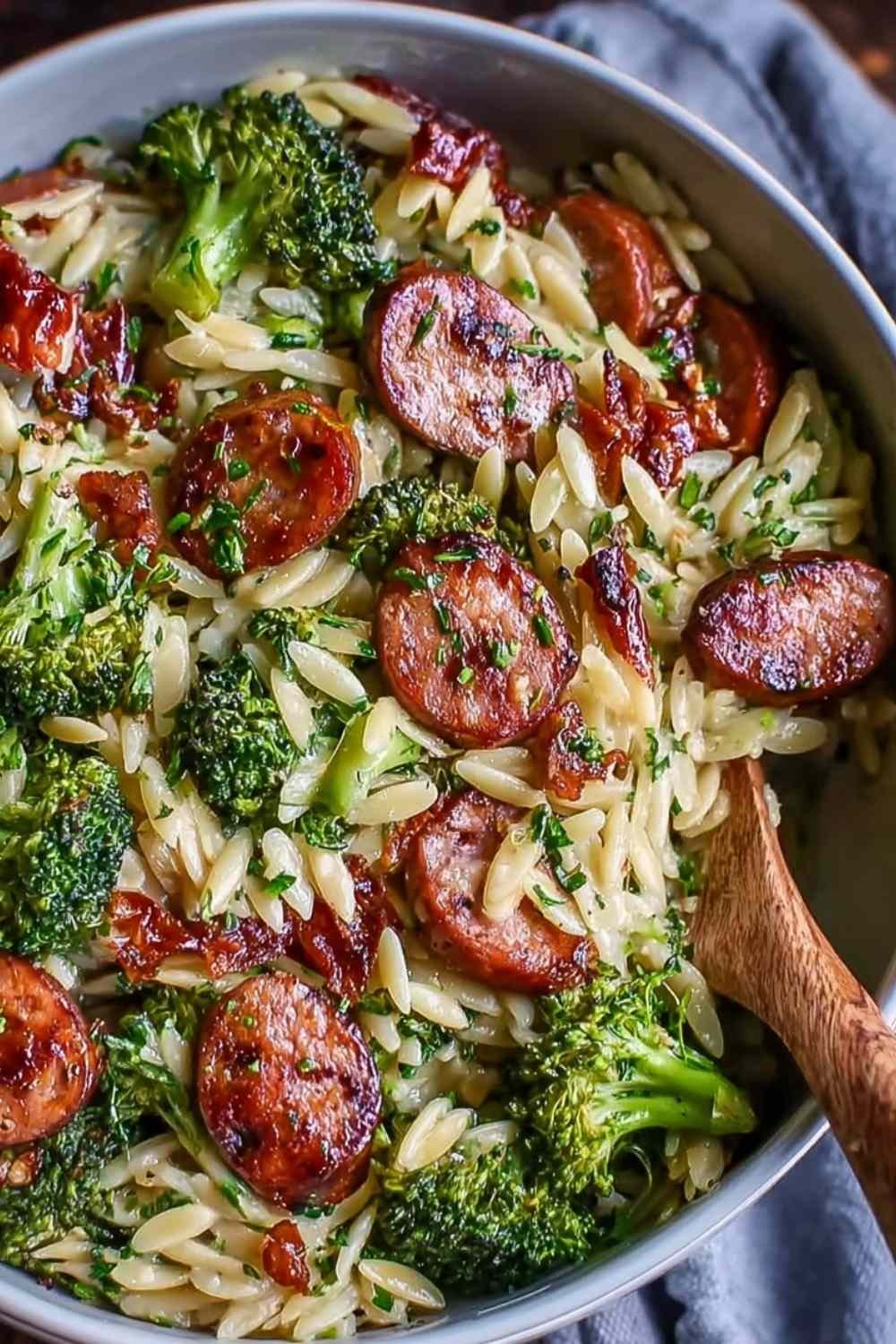 Chicken sausage broccoli orzo in white bowl topped with parmesan cheese and fresh parsley