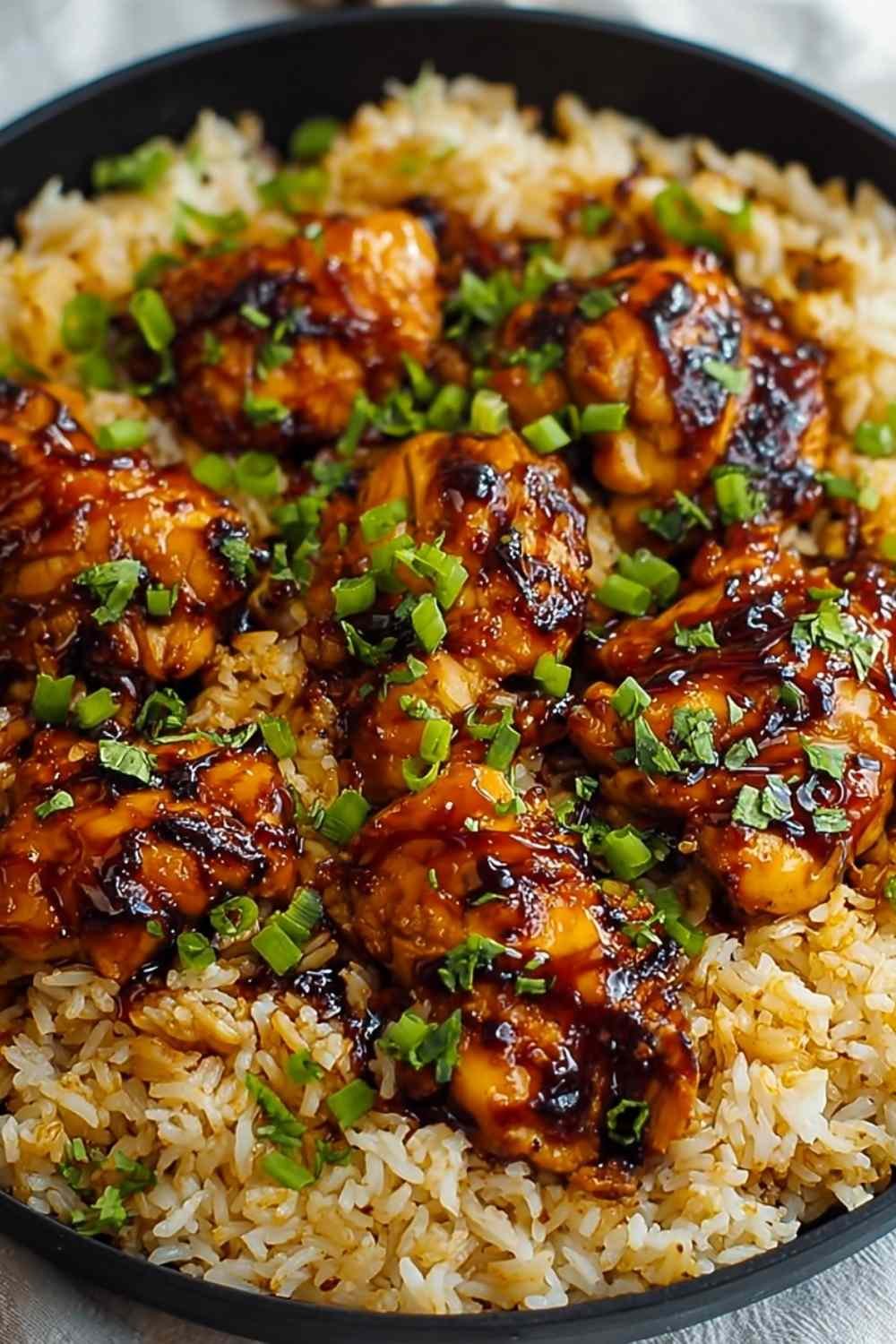 Honey BBQ Chicken Rice with glazed chicken thighs over fluffy rice garnished with green onions in cast iron skillet