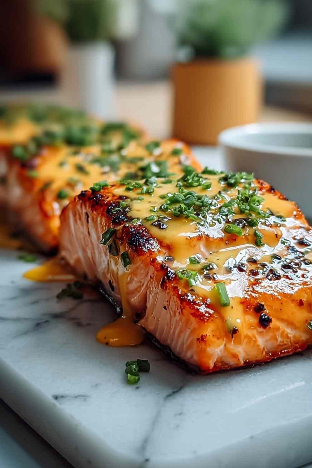 Bang Bang Salmon fillets drizzled with creamy sweet chili sauce and garnished with green onions on white plate