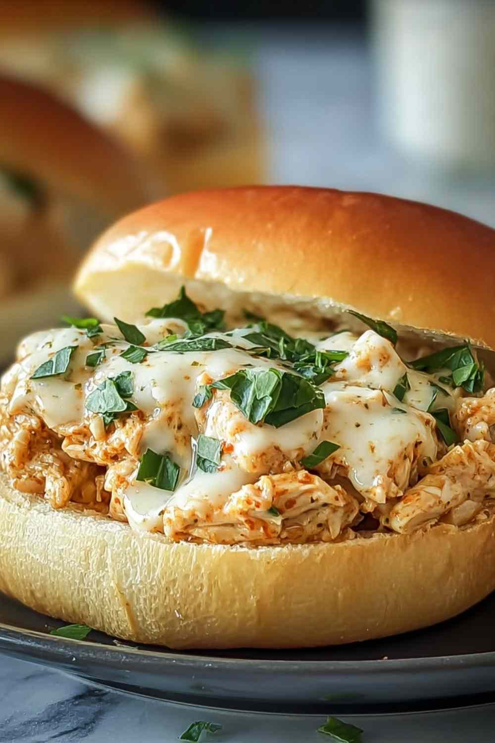 Chicken Alfredo Sloppy Joe on toasted bun with creamy sauce and fresh parsley garnish