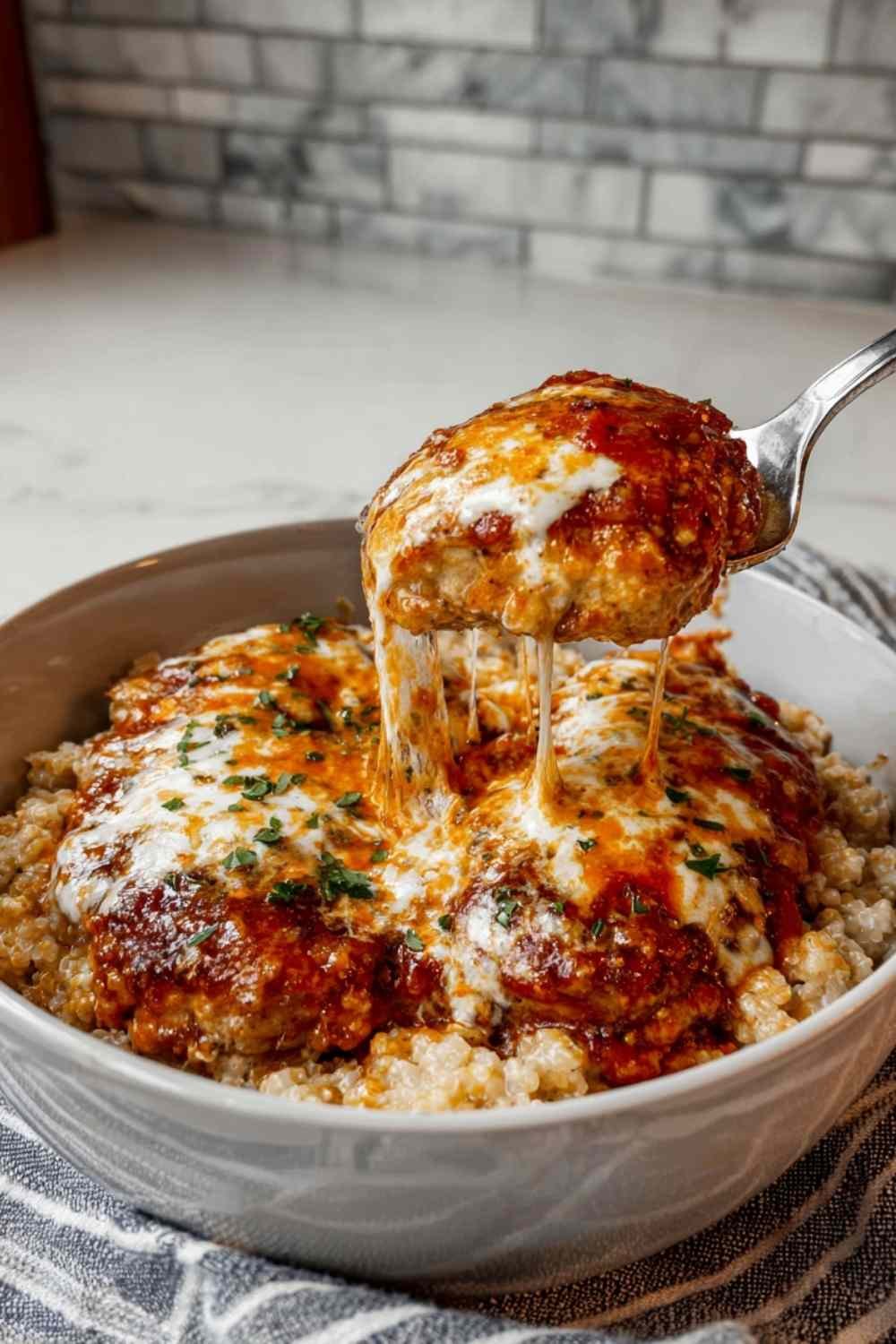Cottage cheese chicken parm bowl topped with melted mozzarella and fresh basil in white bowl