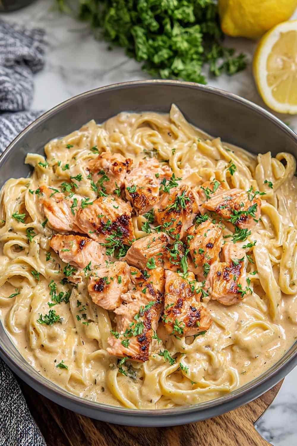 Creamy salmon pasta with fettuccine, flaked salmon, and parmesan cream sauce in large skillet with fresh dill