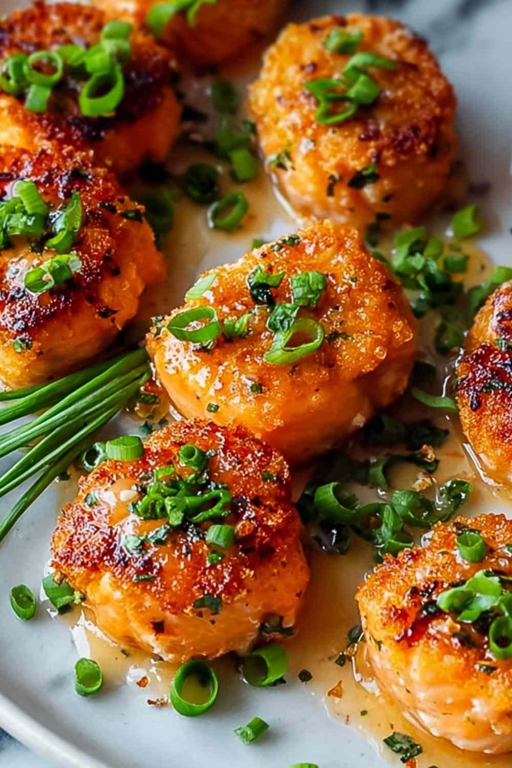 Bang Bang Salmon bites drizzled with sweet and spicy sauce on serving plate with lime garnish