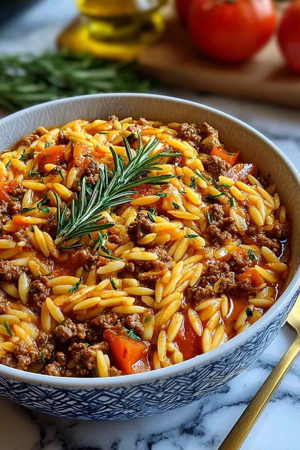 Ground beef orzo recipe in large skillet with melted parmesan cheese and herbs