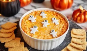 Halloween Buffalo Chicken Dip topped with ghost-shaped cheese and olive eyes in baking dish