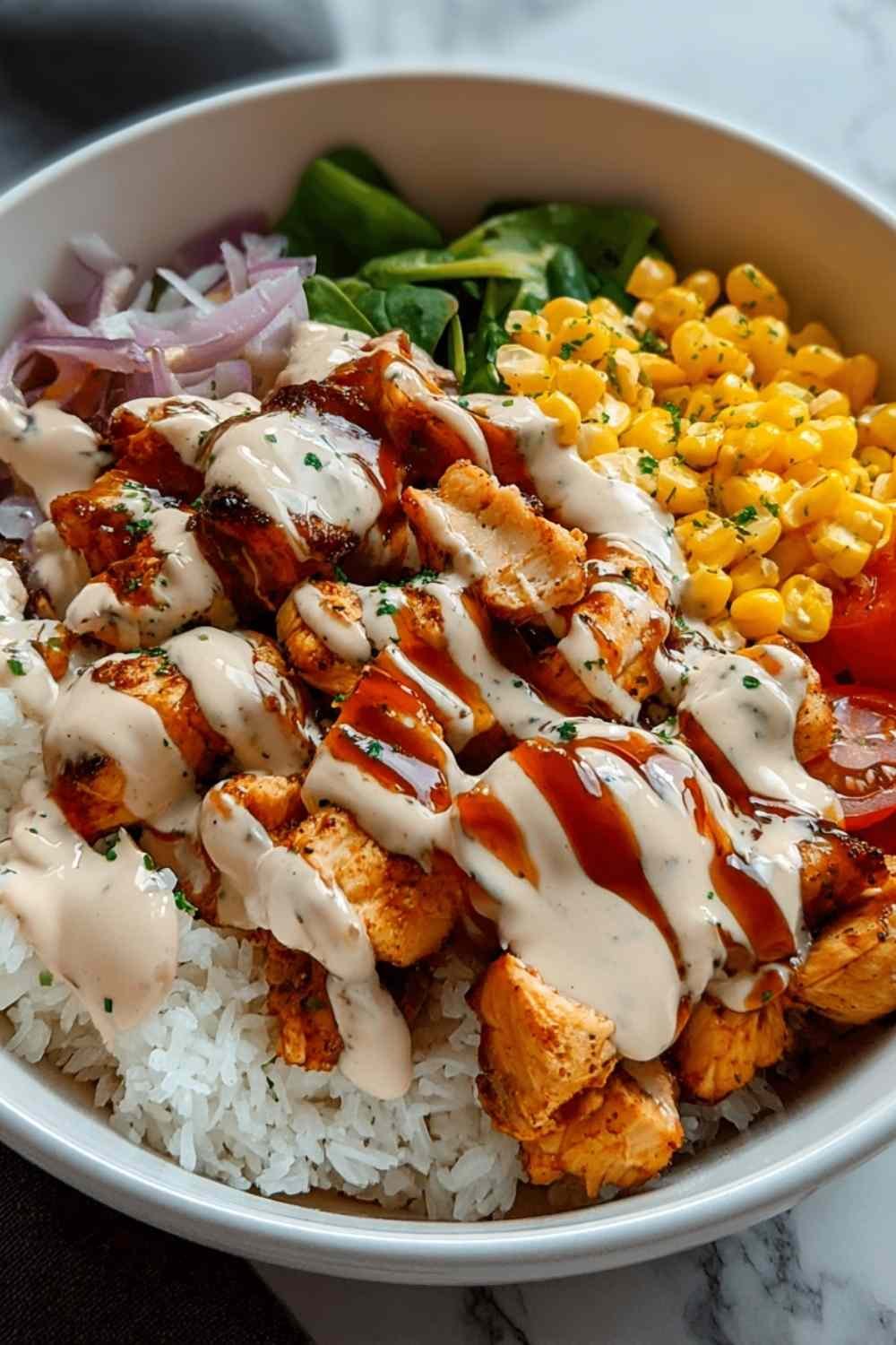 High protein BBQ ranch chicken bowl with grilled chicken strips, corn, black beans, and fresh vegetables topped with creamy sauce