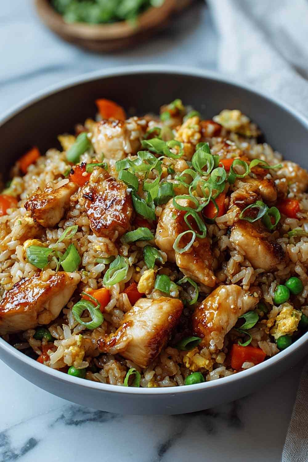 High Protein Crispy Garlic Chicken Fried Rice in a large wok garnished with green onions and sesame seeds