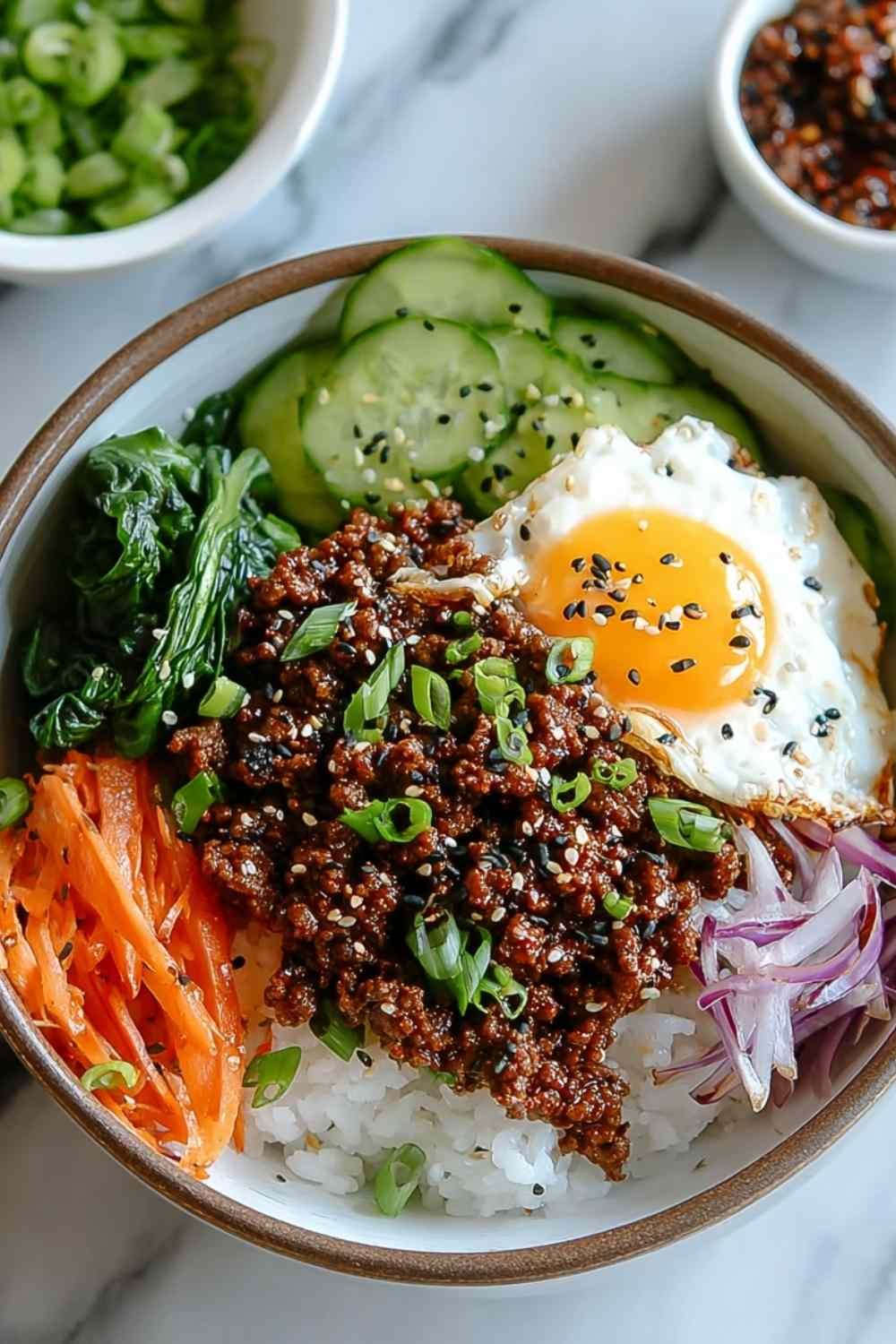 Korean Ground Beef Bowl with rice topped with sesame seeds and green onions in white bowl