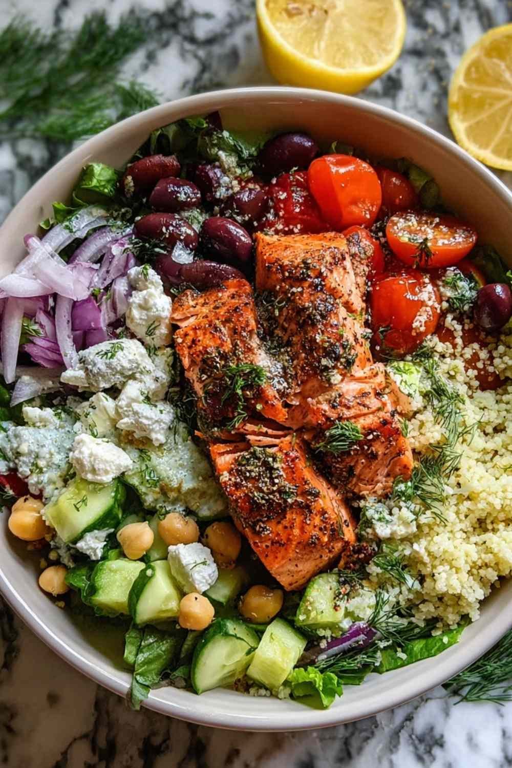 Mediterranean Salmon Bowl with baked salmon, quinoa, fresh vegetables, feta cheese, olives, and tzatziki sauce on white plate