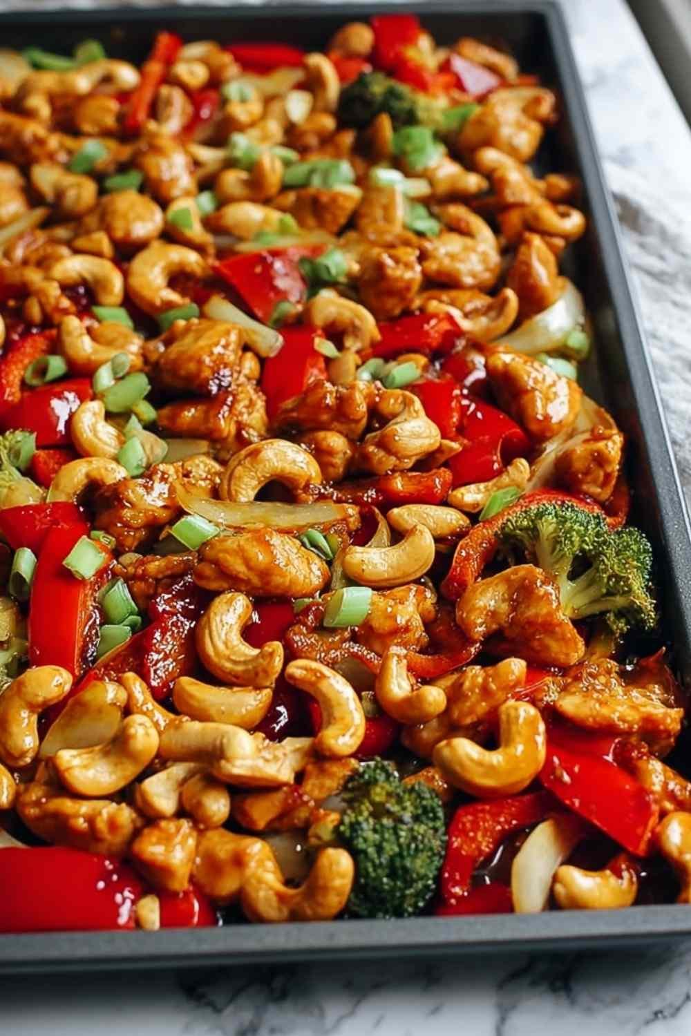 Sheet Pan Cashew Chicken with bell peppers and cashews on white serving platter