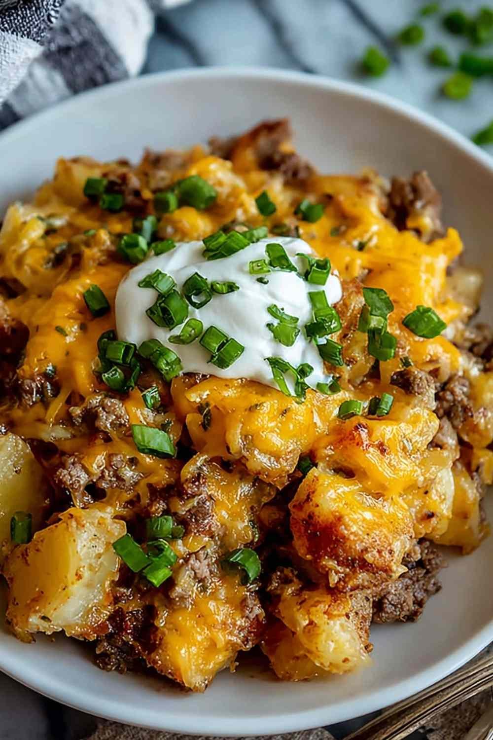 Slow cooker cowboy potato casserole with melted cheese and bacon topping served in white bowl