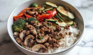 Spicy ground beef stir-fry bowl with colorful vegetables and steamed rice in white bowl
