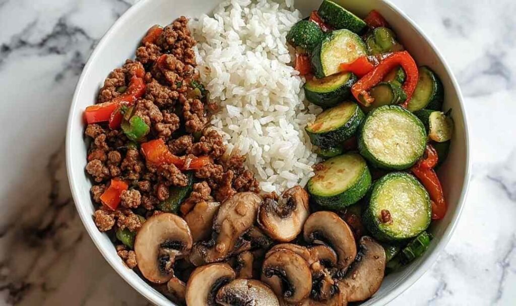Spicy ground beef stir-fry bowl with colorful vegetables and steamed rice in white bowl