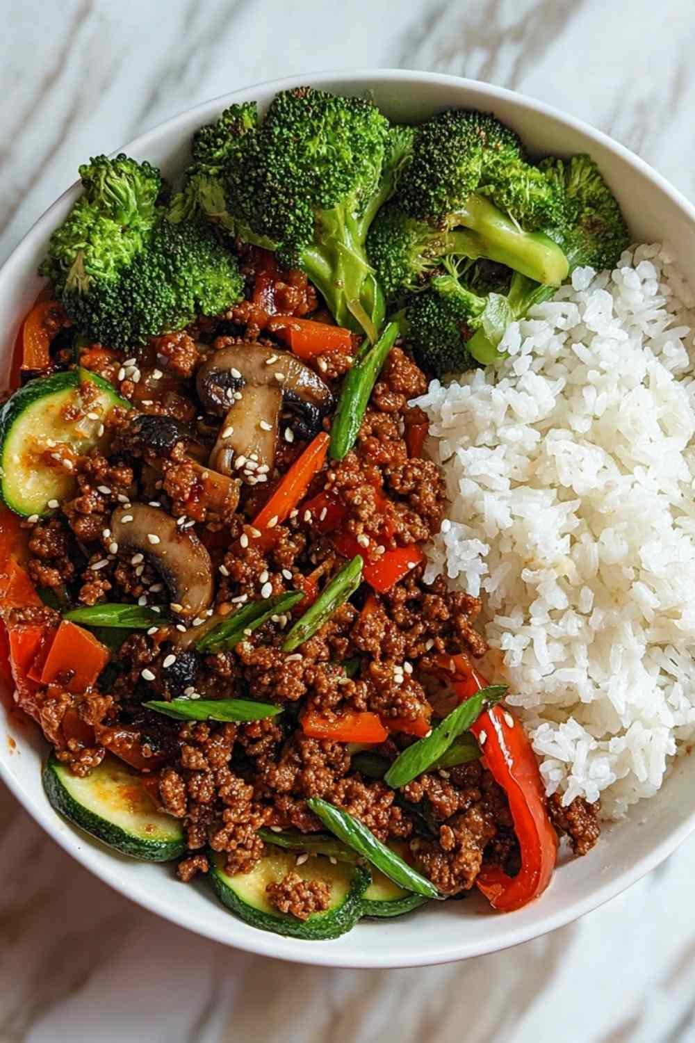 Spicy ground beef stir-fry bowl with colorful vegetables and steamed rice in white bowl