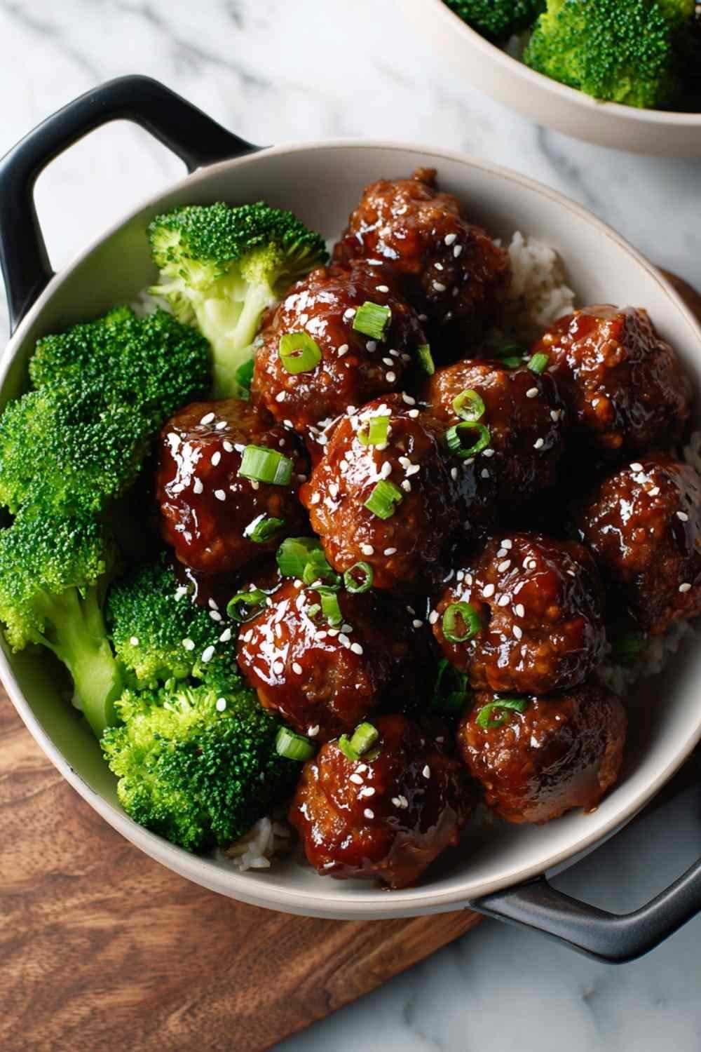 Sticky Mongolian meatballs and broccoli coated in glossy sauce in a skillet with sesame seeds