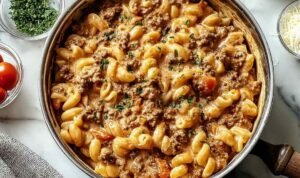Creamy ground beef pasta in skillet with melted parmesan cheese and Italian herbs