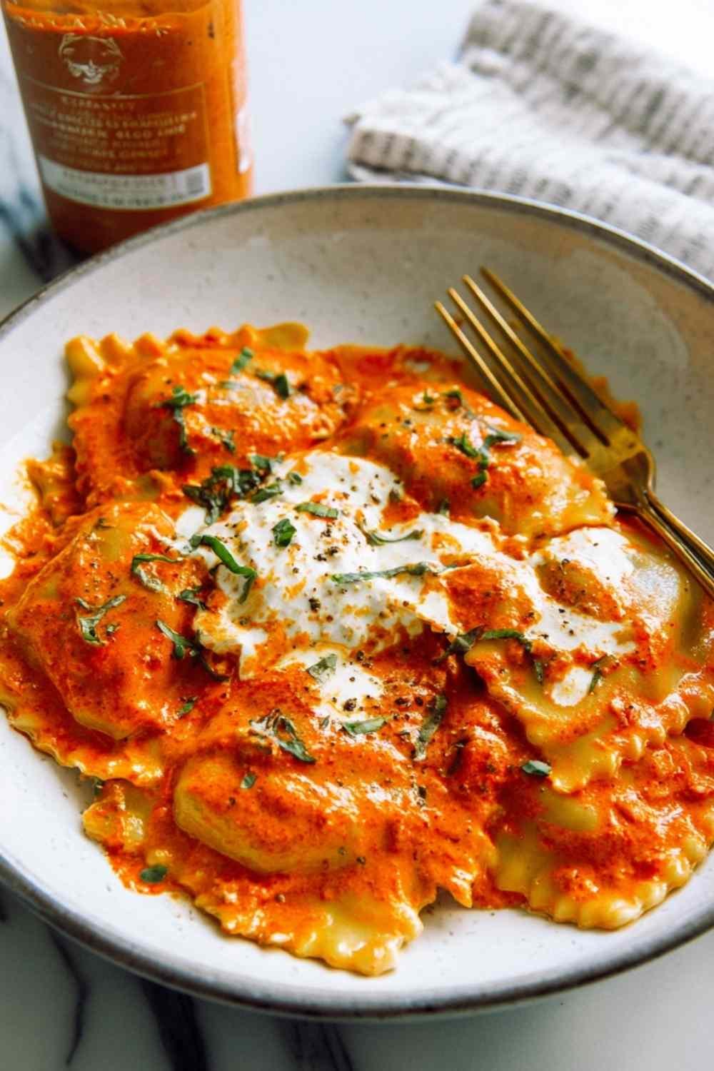 Trader Joe's tomato burrata ravioloni with spicy vodka sauce topped with fresh burrata and parmesan cheese on white plate