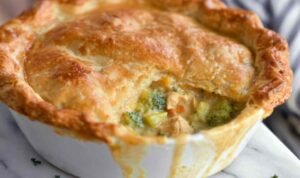 Golden baked broccoli cheddar chicken pot pie with flaky crust and steam rising from center slits