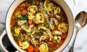 Hearty Chicken Tortellini Soup with vegetables and cheese tortellini in a white bowl