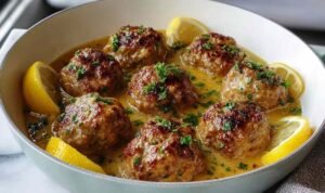 Greek meatballs in lemon sauce simmering in pot with herbs and creamy avgolemono coating