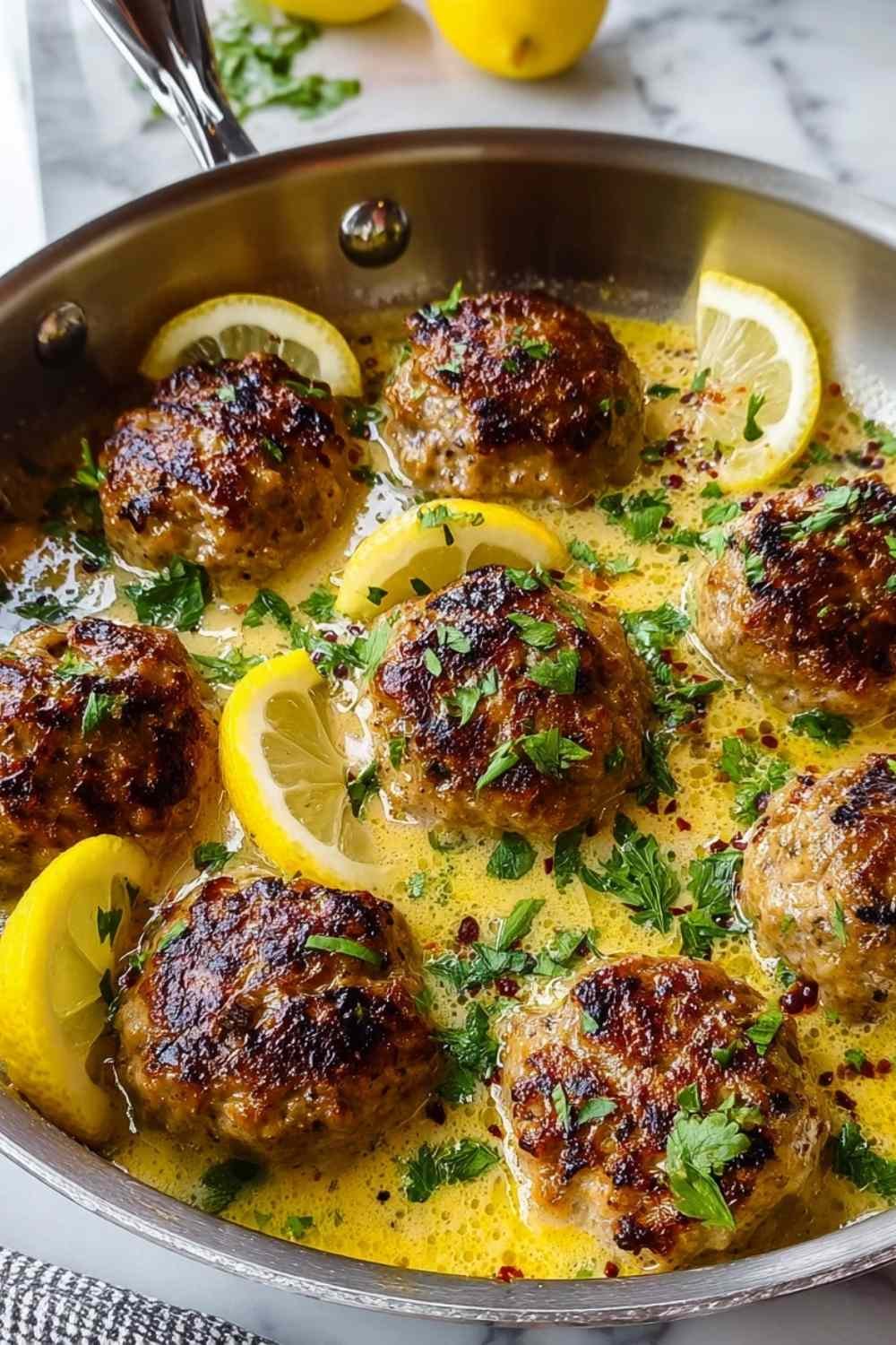 Greek meatballs in lemon sauce simmering in pot with herbs and creamy avgolemono coating