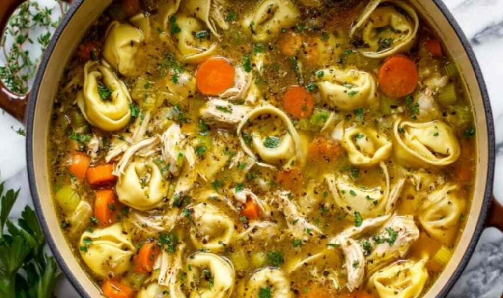 Chicken tortellini soup with seared chicken, cheese tortellini, vegetables, and Parmesan garnish in white bowl