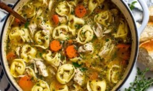 Chicken tortellini soup with seared chicken, cheese tortellini, vegetables, and Parmesan garnish in white bowl