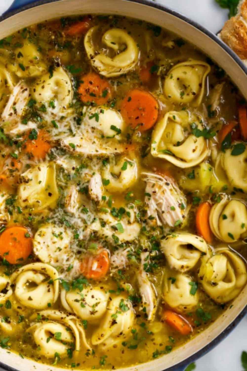 Chicken tortellini soup with seared chicken, cheese tortellini, vegetables, and Parmesan garnish in white bowl