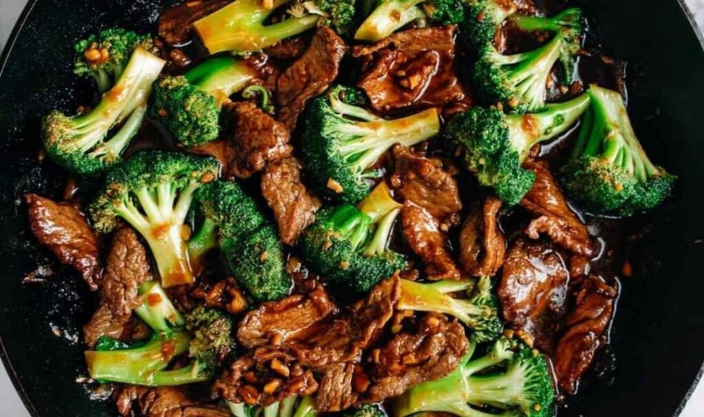 Chinese beef and broccoli in a large nonstick skillet with glossy brown sauce, lightly charred beef slices, and bright green broccoli florets