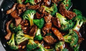 Chinese beef and broccoli in a large nonstick skillet with glossy brown sauce, lightly charred beef slices, and bright green broccoli florets