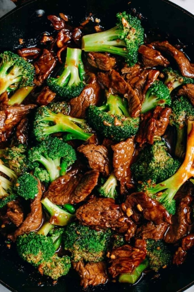Chinese beef and broccoli in a large nonstick skillet with glossy brown sauce, lightly charred beef slices, and bright green broccoli florets