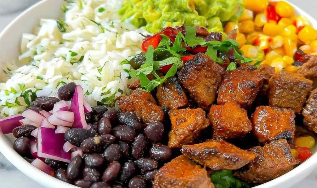 Copycat Chipotle steak sliced and cubed, served on a plate with cilantro lime rice, black beans, and fresh pico de gallo for an easy weeknight dinner