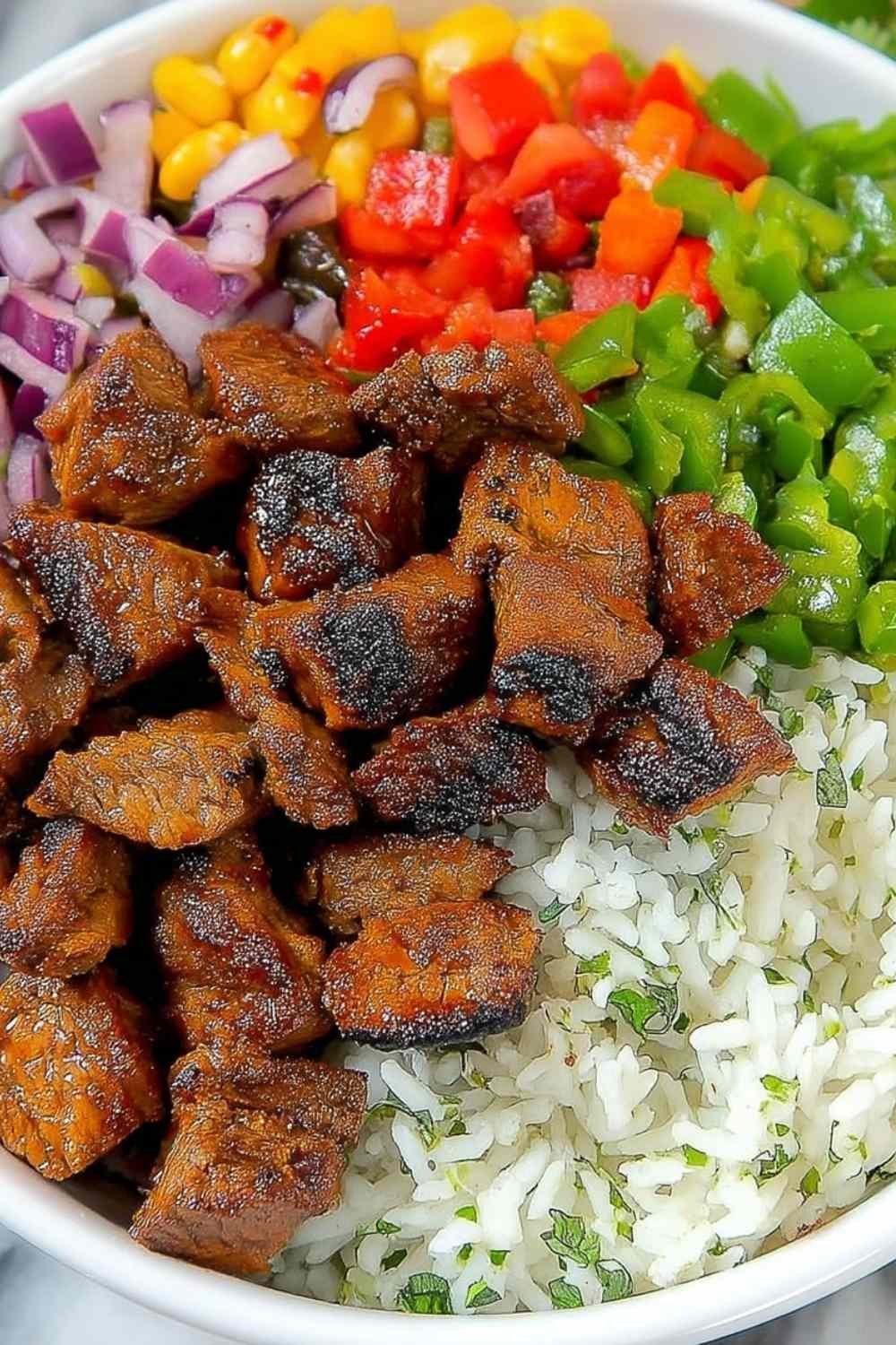 Copycat Chipotle steak sliced and cubed, served on a plate with cilantro lime rice, black beans, and fresh pico de gallo for an easy weeknight dinner