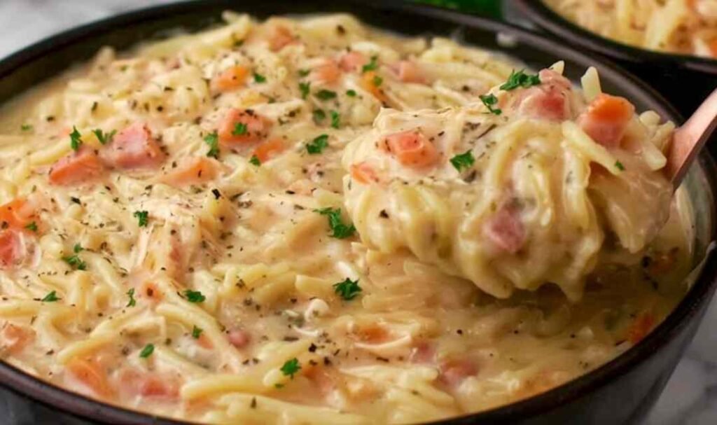 Crack chicken noodle soup in a white bowl with shredded chicken pasta noodles crumbled crispy bacon and melted cheddar cheese in a creamy ranch broth