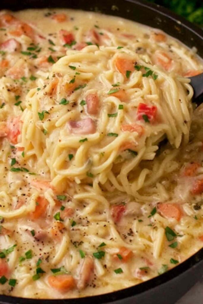 Crack chicken noodle soup in a white bowl with shredded chicken pasta noodles crumbled crispy bacon and melted cheddar cheese in a creamy ranch broth