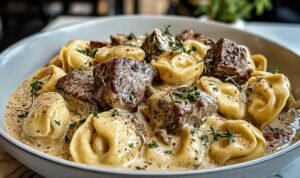 Cracked garlic steak tortellini in creamy sauce on white plate garnished with parsley