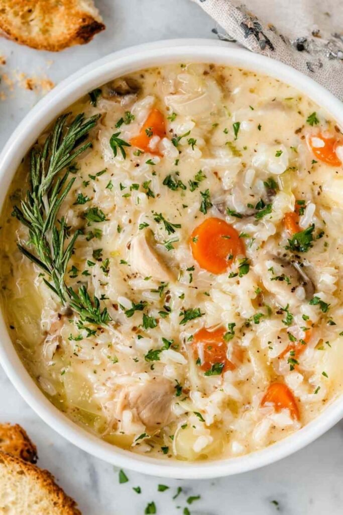 Bowl of creamy chicken and rice soup garnished with parmesan cheese and fresh parsley