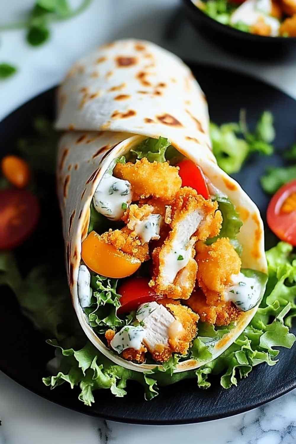 A crispy chicken ranch snack wrap sliced in half diagonally on a wooden board, showing the golden breaded chicken, melted cheddar, fresh lettuce, and ranch dressing inside